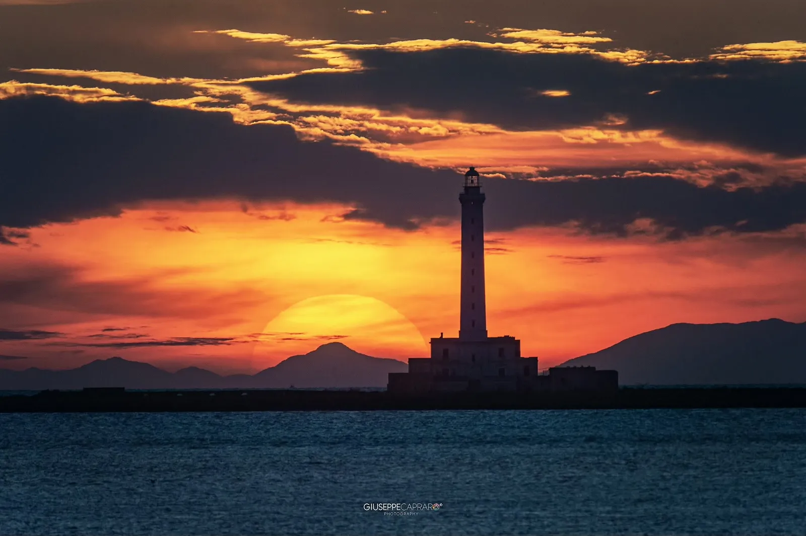 Il faro dentro un tramonto teatrale.